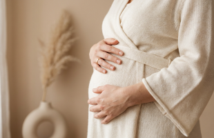 Ventre féminin post-grossesse, mains posées sur l'abdomen, illustrant le diastasis des grands droits